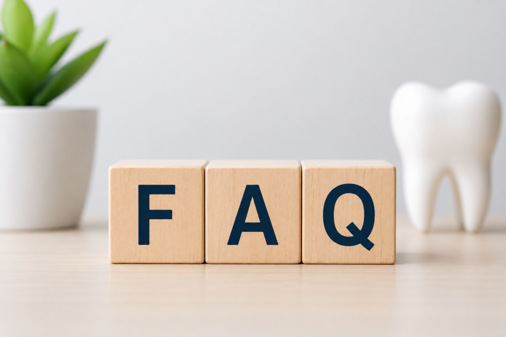Wooden blocks spelling FAQ with a decorative tooth model, representing frequently asked questions about dental treatments and oral health.